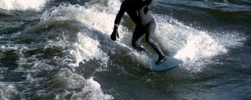 Surfer Riding Wave on a Turquoise Surfboard