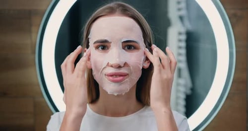 Young Woman Applies Sheet Mask in Modern Bathroom