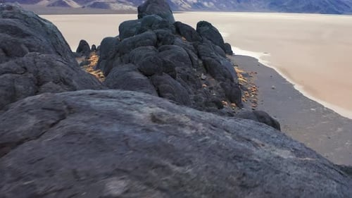 Dark rugged rocks overlooking a vast empty salt flat desert landscape