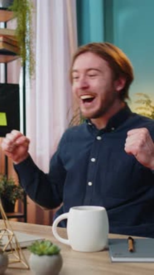 Excited man celebrating success at desk