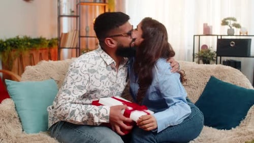 Woman Gives Birthday Gift to Man on Sofa