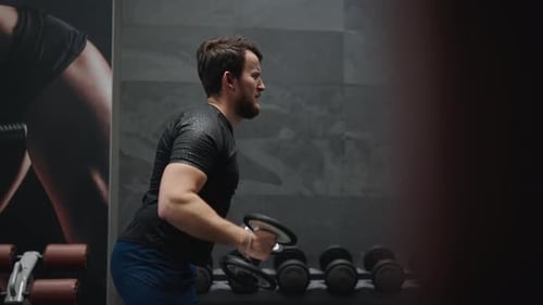 Male do side lateral raise with dumbbells, shoulder exercise at indoor gym