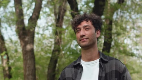 Young Handsome Man in Casual Clothes Walking on an Alley of the City Park with a Confident Face