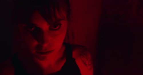 Mujer psicópata con un resplandor enojado en su rostro en una habitación iluminada en rojo oscuro. primer plano