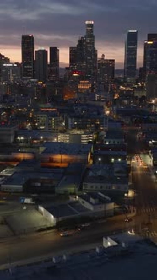 Backwards Fly Above Night City High Rise Business Buildings Against Colourful Sky Los Angeles