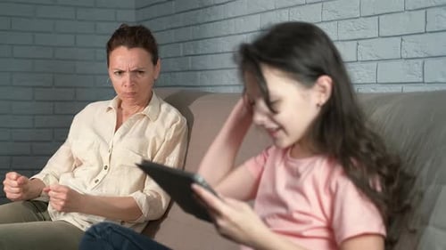 Woman Looking at Child Playing on Tablet Indoors