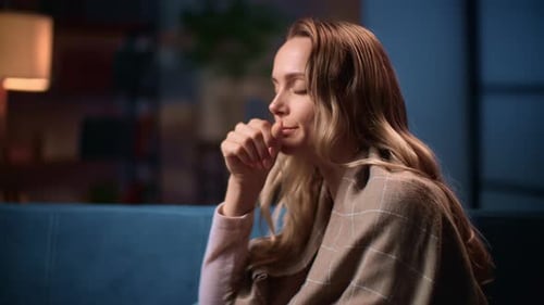 Woman Coughing while Sitting on Couch Inside Home