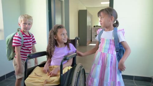 Diverse kids smiling and holding wheelchair in hallway with boy arriving, two packs near, preparing