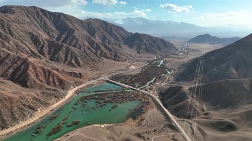 Aerial View of a Bridge Over a Turquoise River in Arid Mountains