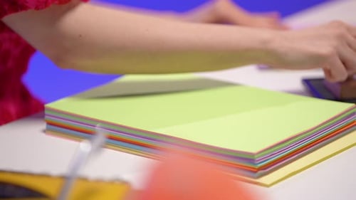 Close-up of hand stamping colorful pastel paper stack in retro office with vibrant lighting and deco
