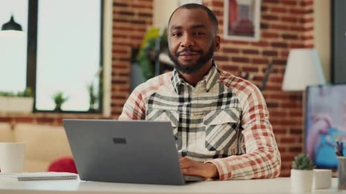 Man Works on Laptop at Desk Indoors