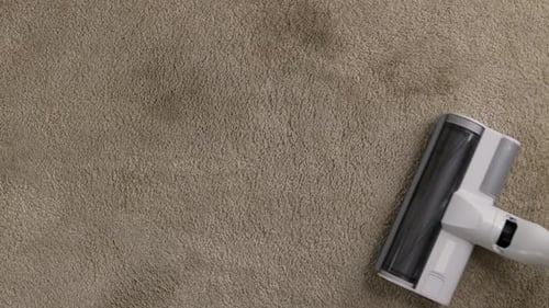 Close Up of Vacuum Cleaner Vacuuming Carpet in Modern Apartment