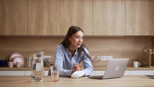 Woman with Prosthetic Using Laptop in Kitchen