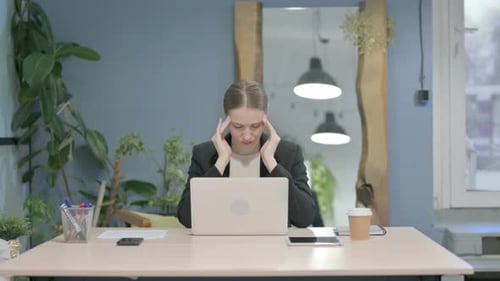 Stressed Woman Massaging Temples at Desk