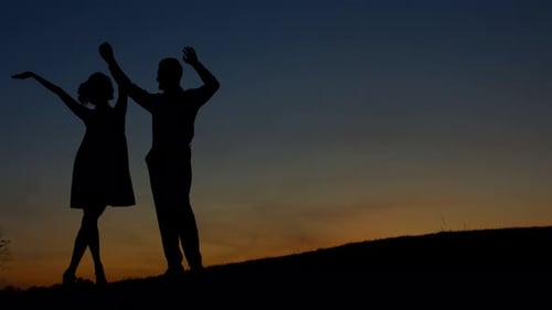 Silhouette Couple Raising Arms at Sunset