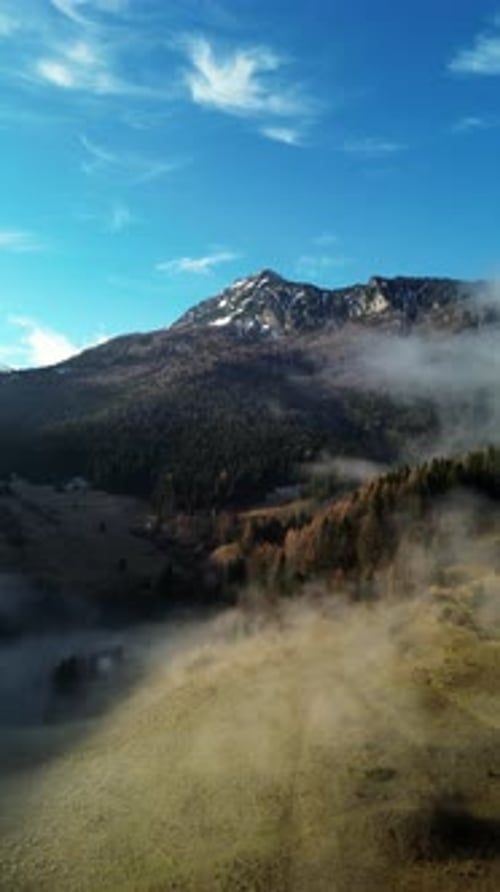 Luftaufnahme der alpinen bergigen ländlichen Landschaft mit Nebel im Tal und blauem HimmelLangsam vorwärts