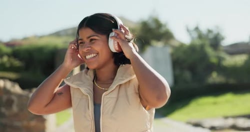 Woman, headphones and dancing in park with music, smile and walk in nature