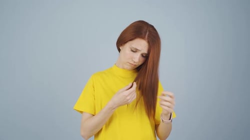 Woman Inspecting Auburn Hair Ends in Studio