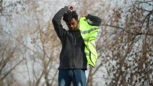 Man in Outdoor Setting Putting on Bright Neon Green Reflective Safety Vest
