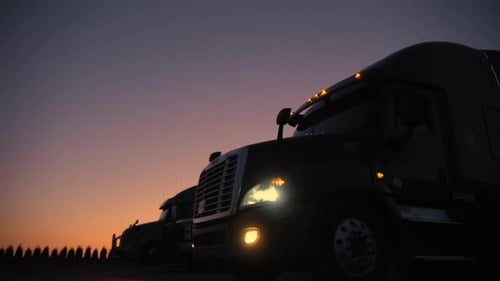 Row of Semi-Trucks Silhouetted at Sunrise