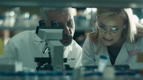 Männliche und weibliche Wissenschaftler arbeiten in einem Labor mit einem Mikroskop und einem Tablet.