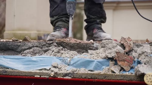 Worker Uses Jackhammer to Break Concrete