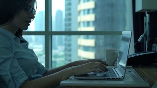 Young businesswoman working on laptop at desk in bright modern office