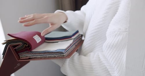 Closeup of Female Hands Choosing Fabric From Color Palette at Textile Showroom