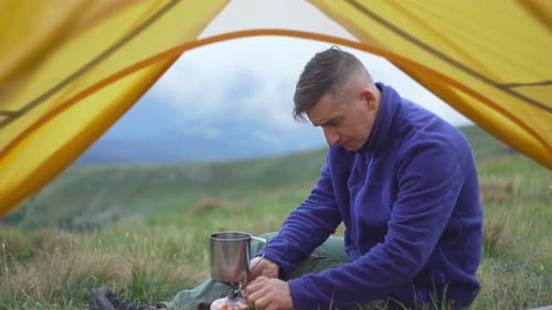 Man Camping, Cooking Food in a Field