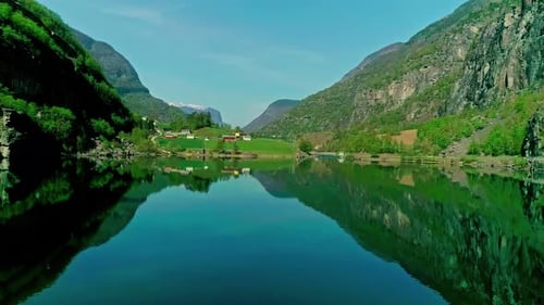 Countryside town on a fjord in Norway - aerial approach over glassy water