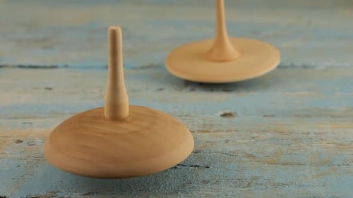 Wooden Spinning Tops Rotate on Blue Table