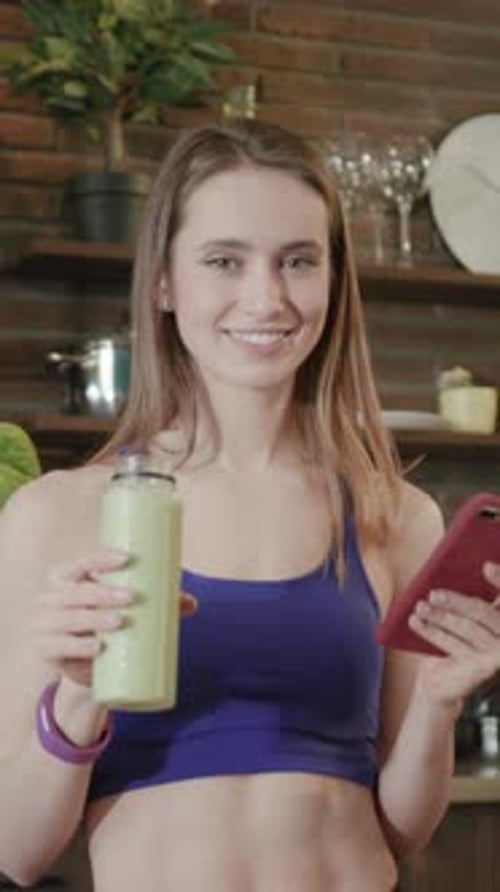 Smiling Woman Holding Smoothie and Tablet Indoors