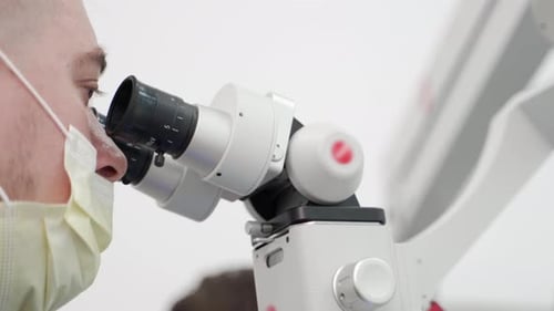 Medical Professional Uses Surgical Microscope in Clinical Setting