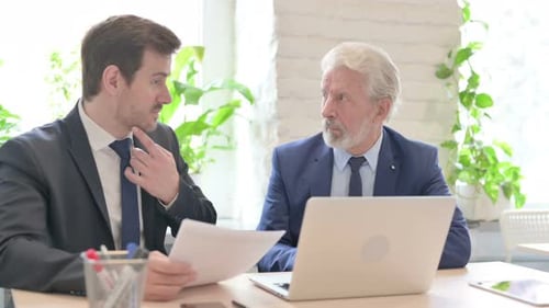 Businessmen Discussing Documents in Office