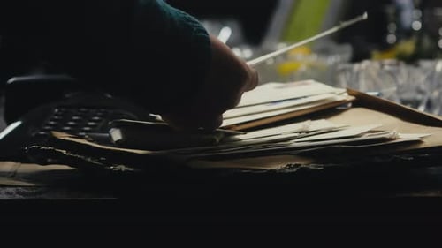 Hands Sorting Through Letters and Documents on Table