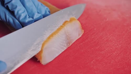 Gloved Hands Slice Smoked Fish on Cutting Board