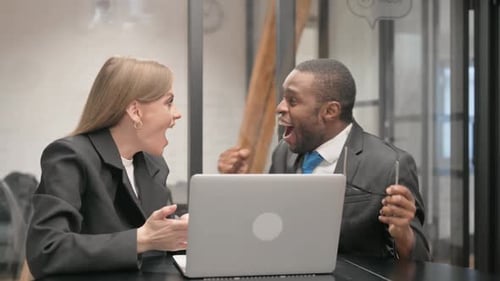 Team Celebrates Success Using Laptop in Office