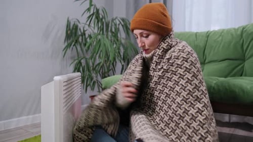 Freezing Woman Warming Hands by Space Heater Indoors