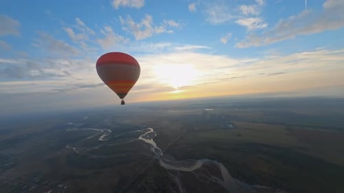Hot Air Balloon Flying over River at Sunrise