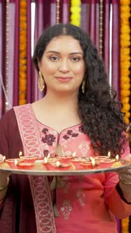Vidéo verticale d'une Indienne tenant un thali rempli de diyas ou de lampes en terre à l'occasion du festival de Diwali