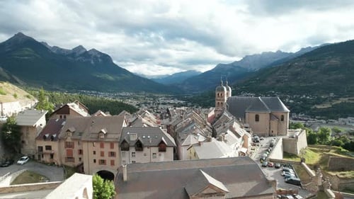 Altes Dorf mit Kirche auf einem bewaldeten Hügel. Luftaufnahme im Tiefflug über die Gebäude von Briancon