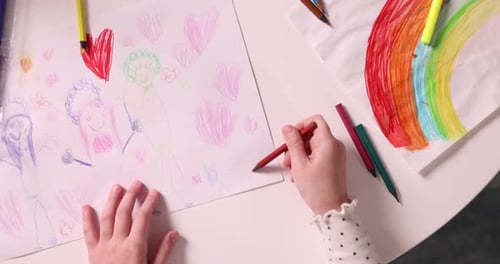 Kleines Mädchen zeichnet mit rotem Stift auf weißem Tisch, Ansicht von oben. Kamera bewegt sich vorwärts