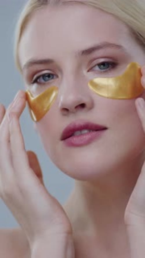 Woman Applies Gold Cosmetic Eye Patches, Close Up