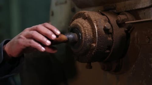 Hand Pushing Rod Through Dusty Industrial Machine