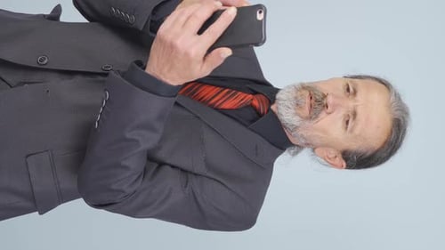Vertikales Video eines chattenden alten Geschäftsmannes.