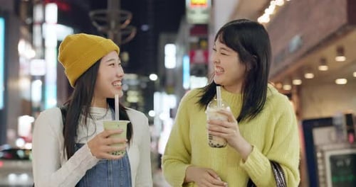 Japoneses, bebidas y amigos paseando por la ciudad por la noche con una feliz conversación sobre viajes