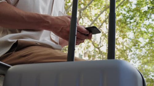 Young Man Walking to the Airport Pulling Suitcase Baggage Use His Phone with Voice Recognition Audio