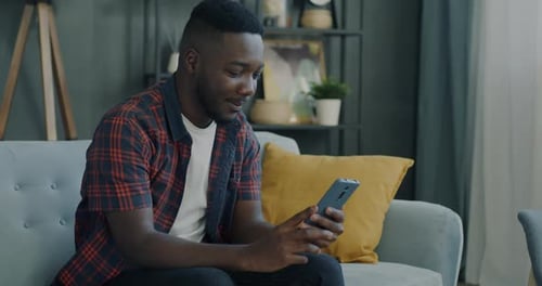 Man Video Chats on Smartphone from Couch