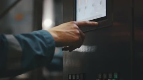 Engineer operating touch screen control panel in factory