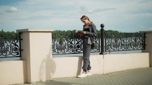 Woman Reading a Book by the Waterfront
